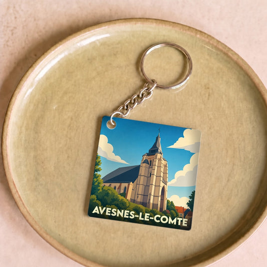 Porte-clés souvenir de la ville d'Avesnes-le-Comte avec une illustration stylisée de son église.