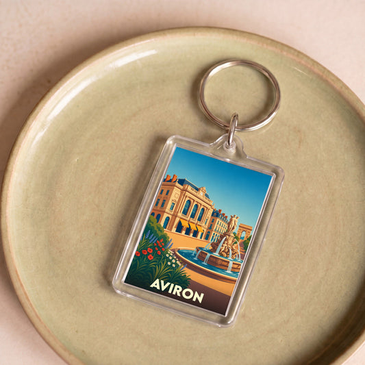 Porte-clés souvenir de la ville d'Aviron avec une illustration stylisée d'une place animée.