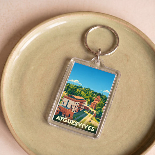 Porte-clés souvenir de la ville de Ayguesvives avec une illustration paysagère stylisée.
