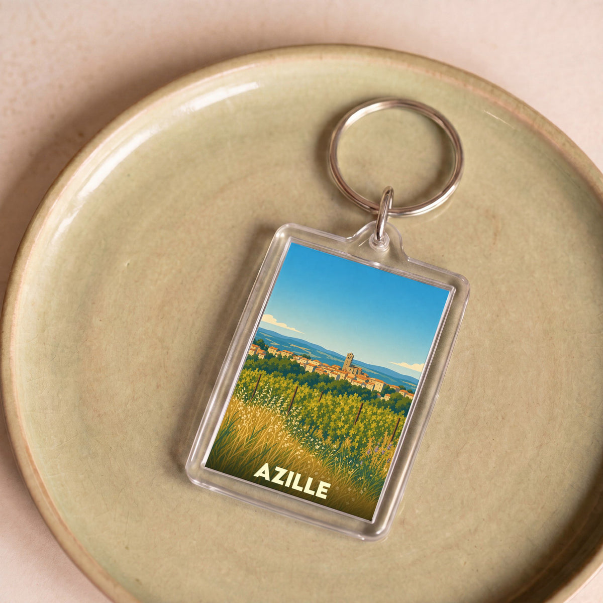 Porte-clés souvenir de la ville d'Azille avec une illustration stylisée de son paysage.