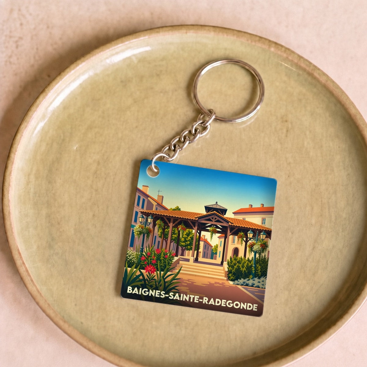 Porte-clés souvenir de la ville de Baignes-Sainte-Radegonde avec une illustration stylisée.