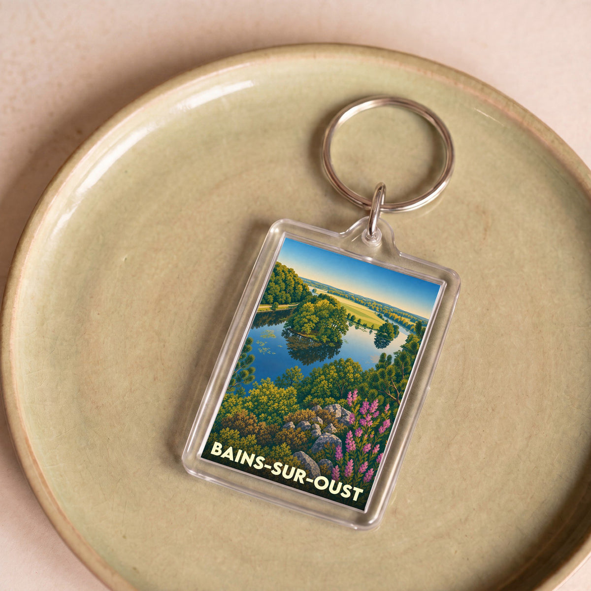 Porte-clés souvenir de la ville de Bains-sur-Oust avec une illustration de paysage coloré.