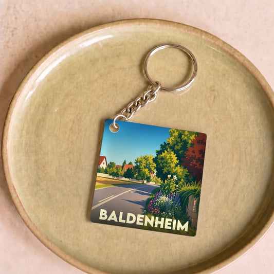 Porte-clés souvenir de la ville de Baldenheim avec une illustration paysagère stylisée.