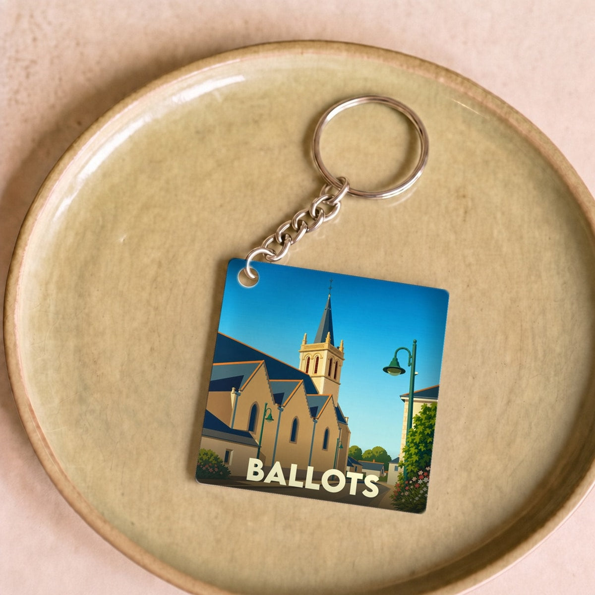 Porte-clés souvenir de la ville de Ballots avec une illustration stylisée de son église.