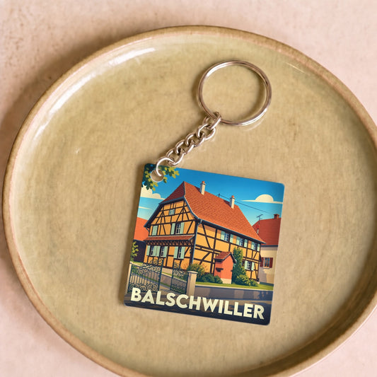 Porte-clés souvenir de la ville de Balschwiller orné d'une illustration stylisée d'une maison à colombages.