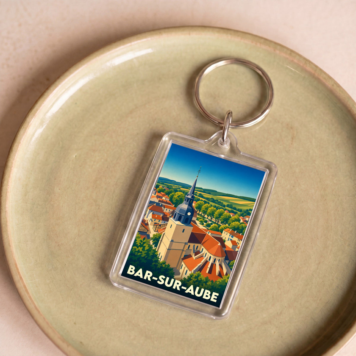 Porte-clés souvenir de la ville de Bar-sur-Aube avec une illustration stylisée de son église et de ses paysages.