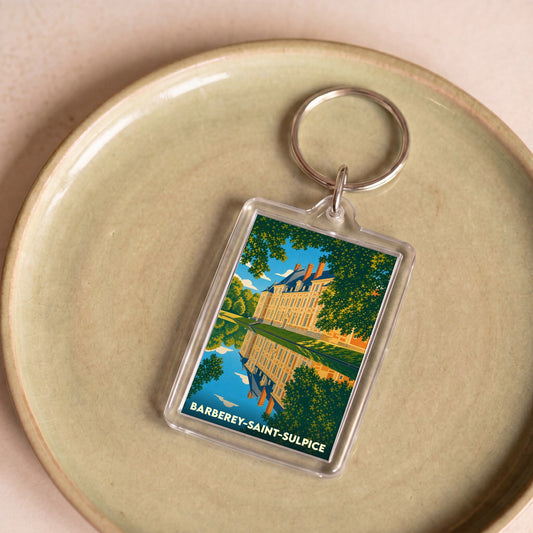 Porte-clés souvenir de la ville de Barberey-Saint-Sulpice avec une illustration stylisée de son château se reflétant dans l'eau.