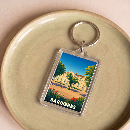 Porte-clés souvenir de la ville de Barbières avec une illustration stylisée d'un bâtiment ensoleillé.