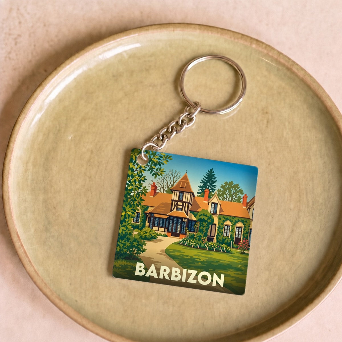 Porte-clés souvenir de la ville de Barbizon avec une illustration stylisée d'une maison de campagne.