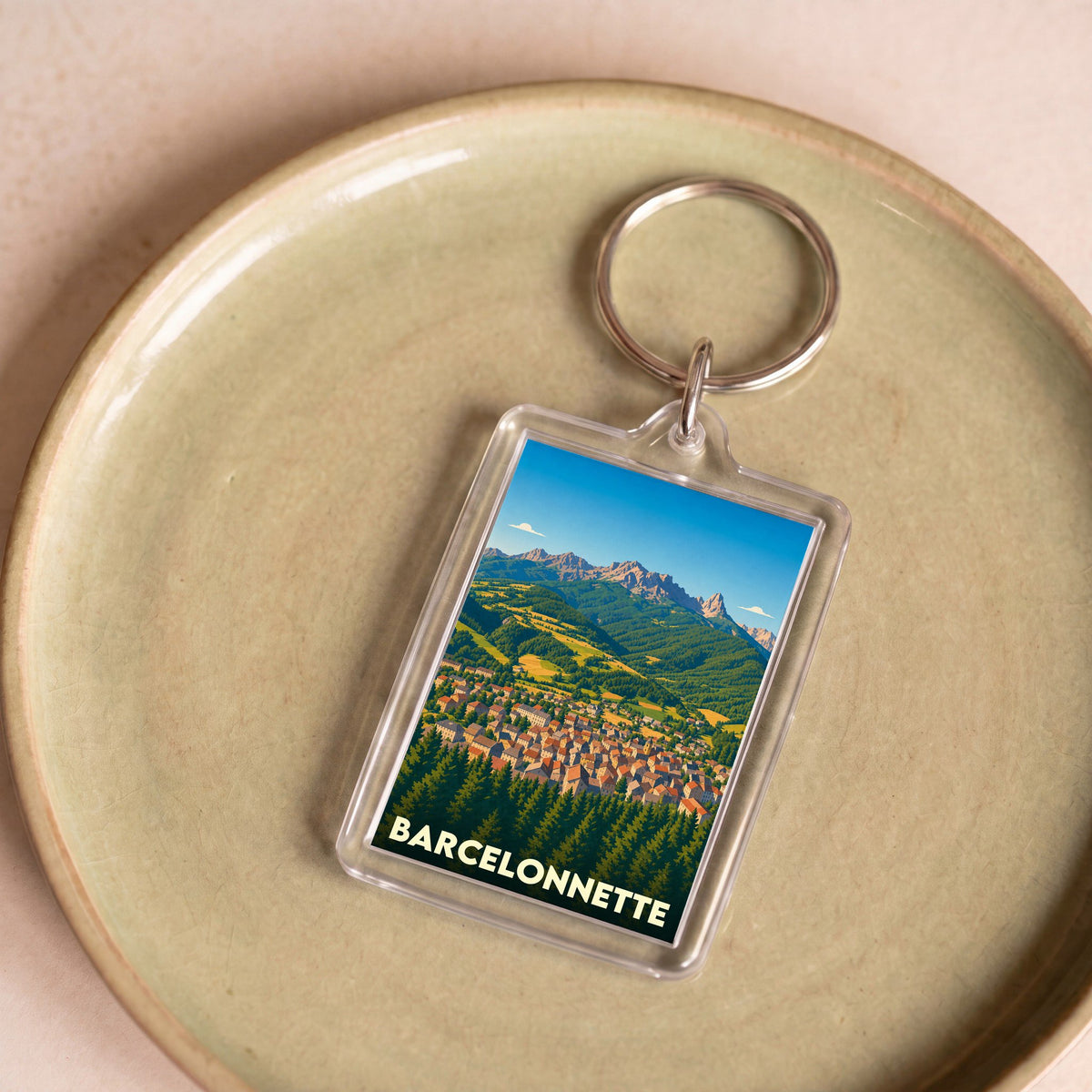 Porte-clés souvenir de la ville de Barcelonnette avec une illustration stylisée de paysages montagneux.