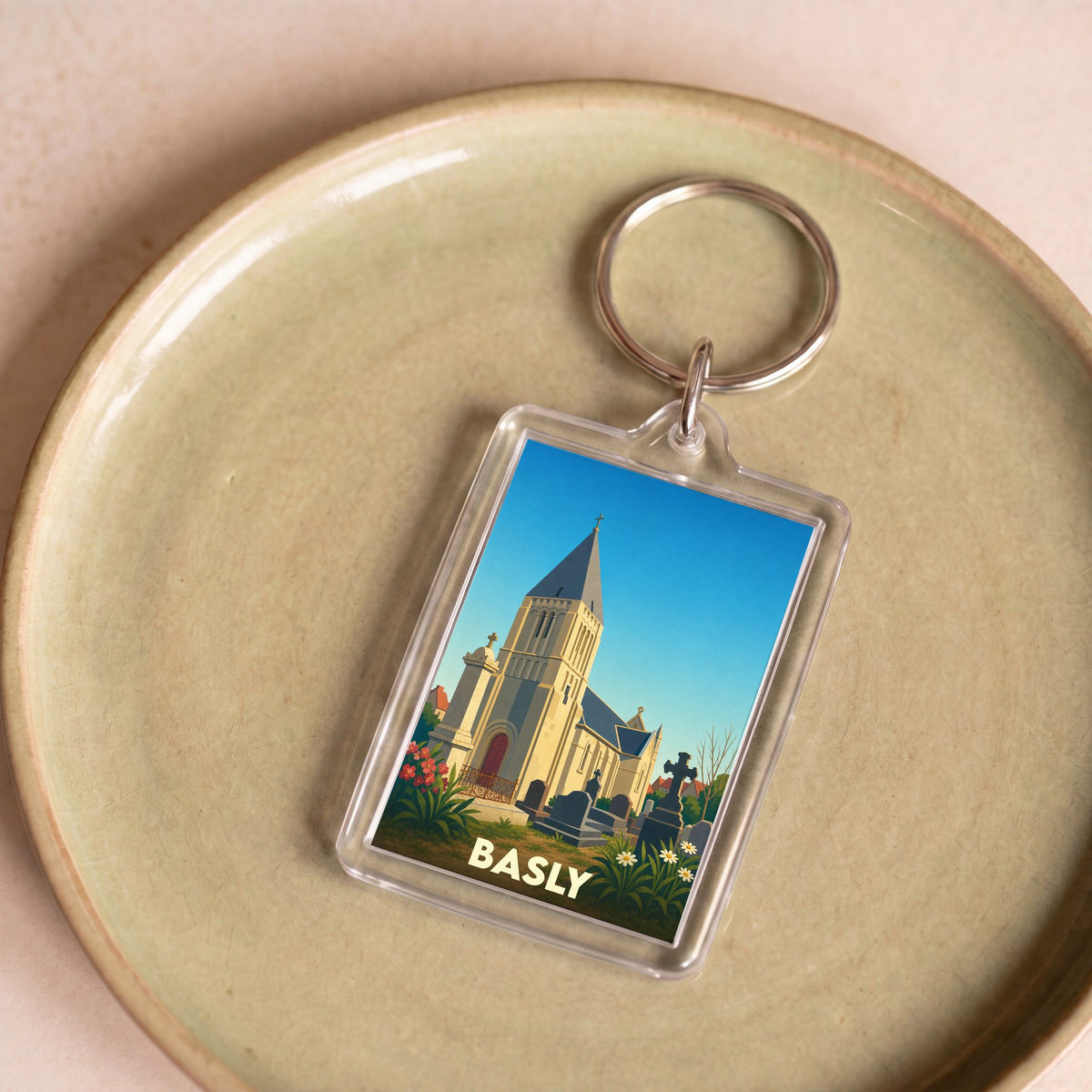 Porte-clés souvenir de la ville de Basly avec une illustration stylisée de son église et de son cimetière.