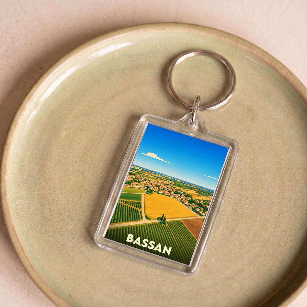 Porte-clés souvenir de la ville de Bassan avec une illustration stylisée de ses paysages et vignobles.
