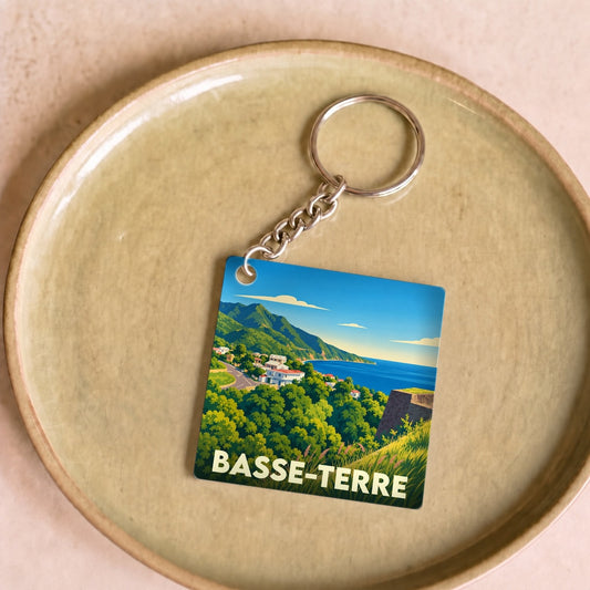 Porte-clés souvenir de la ville de Basse-Terre avec une illustration stylisée d'un paysage côtier verdoyant.