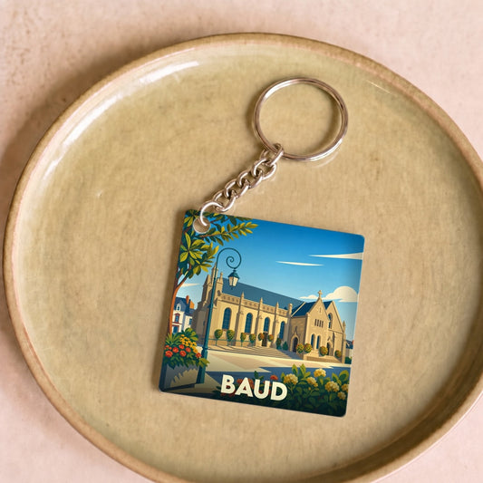 Porte-clés souvenir de la ville de Baud avec une illustration stylisée d'une église sous un ciel bleu.