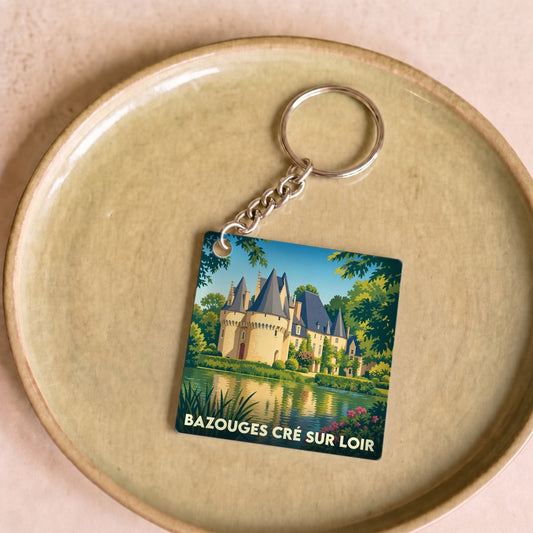 Porte-clés souvenir de la ville de Bazouges Cré sur Loir avec une illustration stylisée de son château au bord de l'eau.