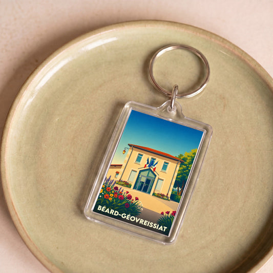 Porte-clés souvenir de la ville de Béard-Géovreissiat avec une illustration stylisée de sa mairie fleurie.