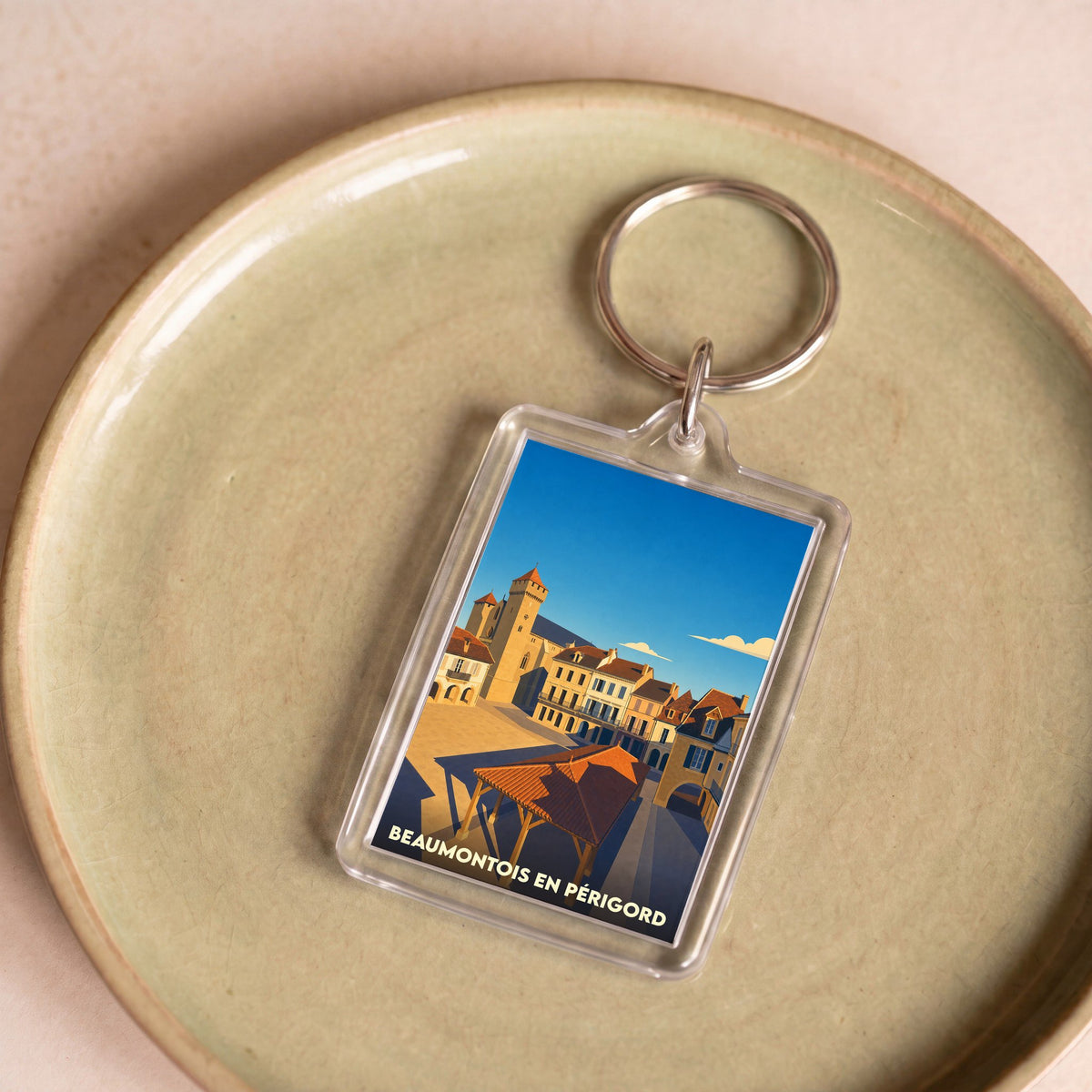 Porte-clés souvenir de Beaumontois en Périgord avec une illustration stylisée de sa place centrale.
