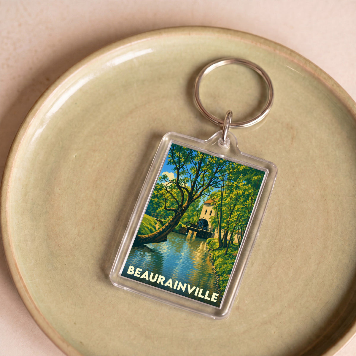 Porte-clés souvenir de la ville de Beaurainville avec une illustration stylisée d'un moulin au bord de l'eau.