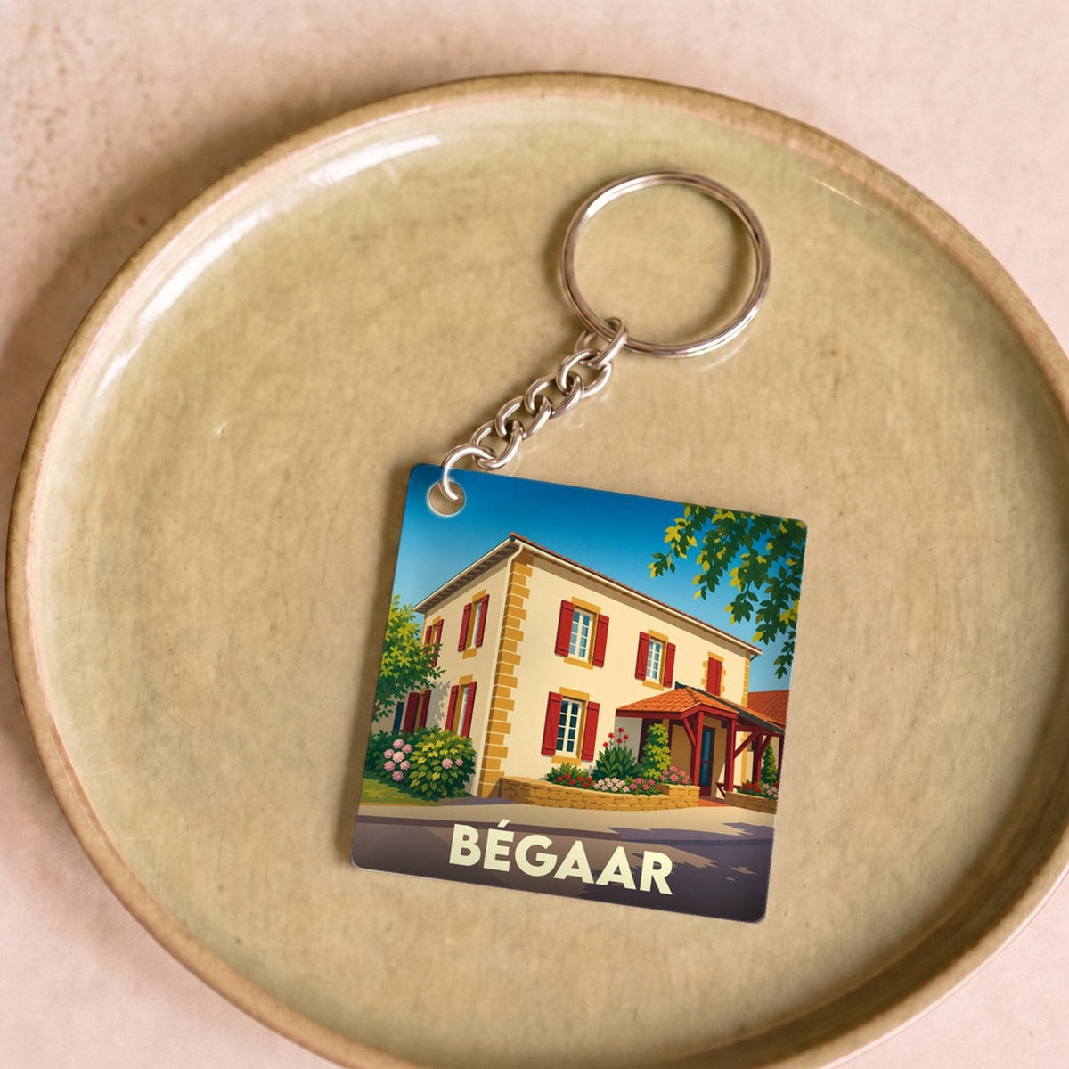 Porte-clés souvenir de la ville de Bégaar avec une illustration stylisée d'une maison landaise.