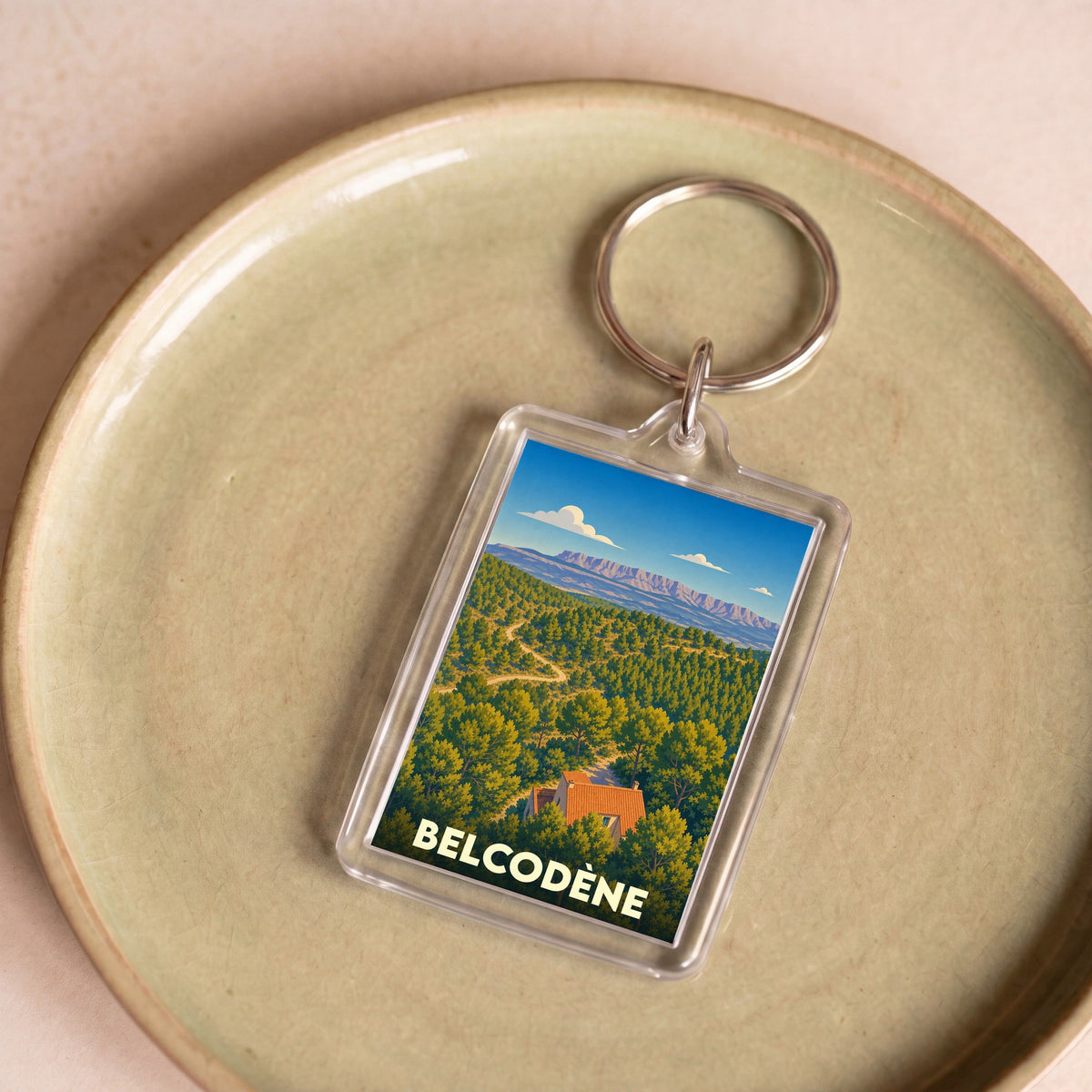 Porte-clés souvenir de la ville de Belcodène avec une illustration stylisée d'un paysage provençal.