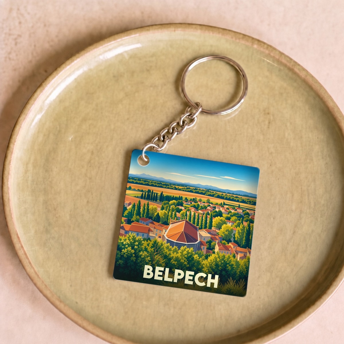 Porte-clés souvenir de la ville de Belpech avec une illustration stylisée d'un paysage ensoleillé.