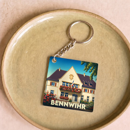 Porte-clés souvenir de la ville de Bennwihr avec une illustration stylisée de sa mairie fleurie.
