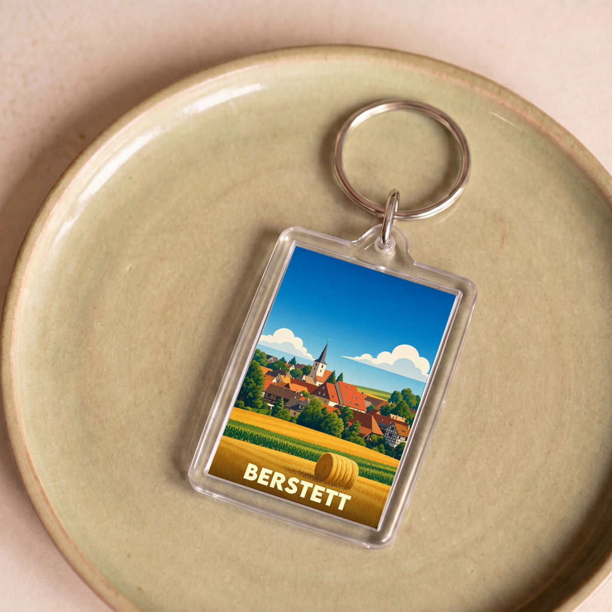 Porte-clés souvenir de la ville de Berstett avec une illustration stylisée d'un paysage alsacien.
