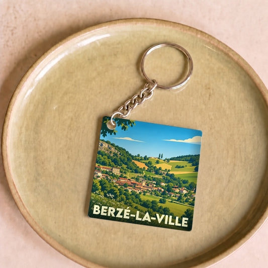 Porte-clés souvenir de la ville de Berzé-la-Ville avec une illustration de paysage vallonné.