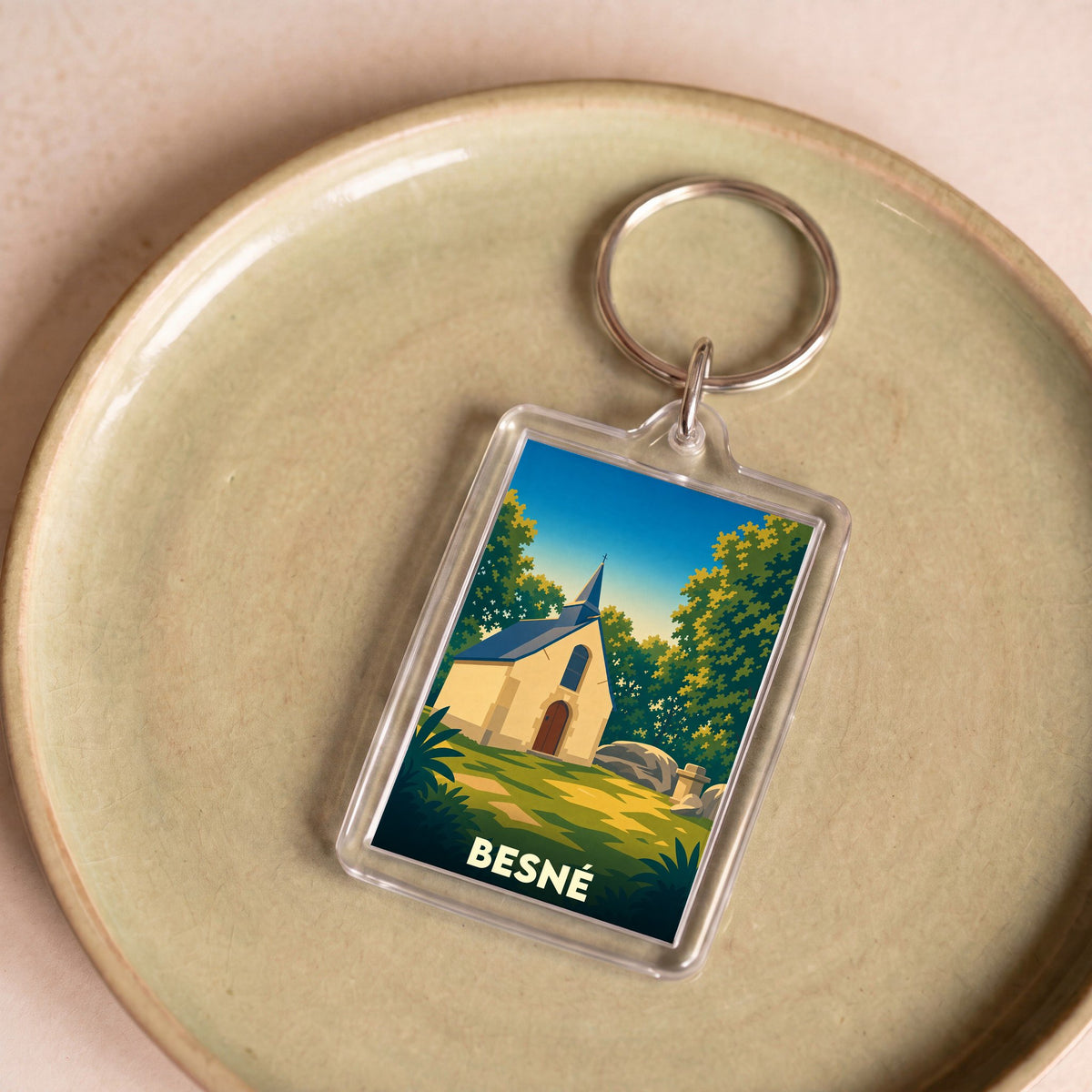 Porte-clés souvenir de la ville de Besné avec une illustration stylisée d'une chapelle en pleine nature.