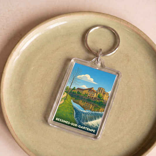 Porte-clés souvenir de Bessines-sur-Gartempe avec une illustration stylisée de la ville au bord de l'eau.