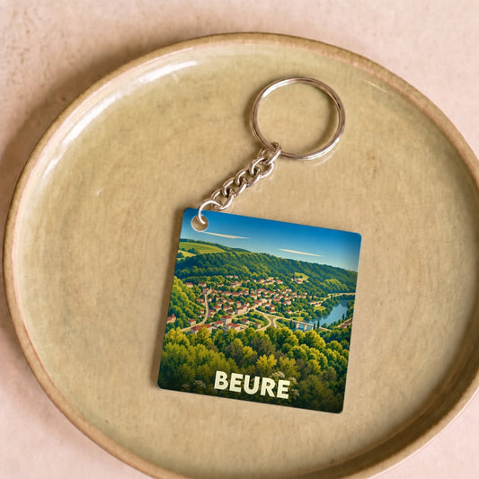 Porte-clés souvenir de la ville de Beure avec une illustration paysagère stylisée.