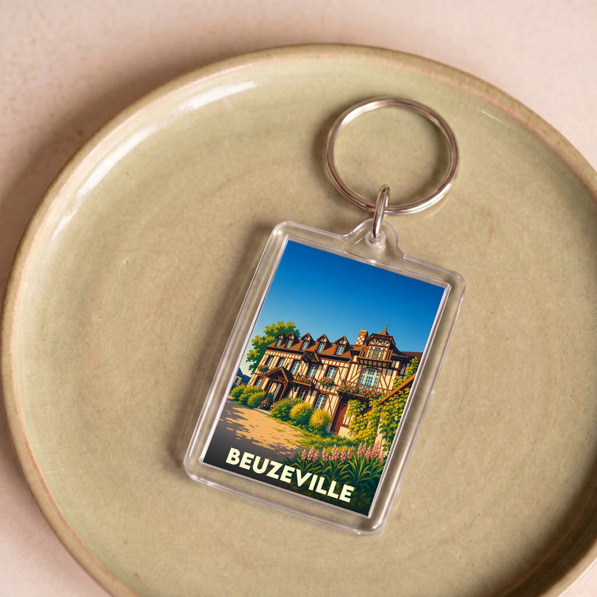Porte-clés souvenir de la ville de Beuzeville avec une illustration stylisée d'une maison normande à colombages.