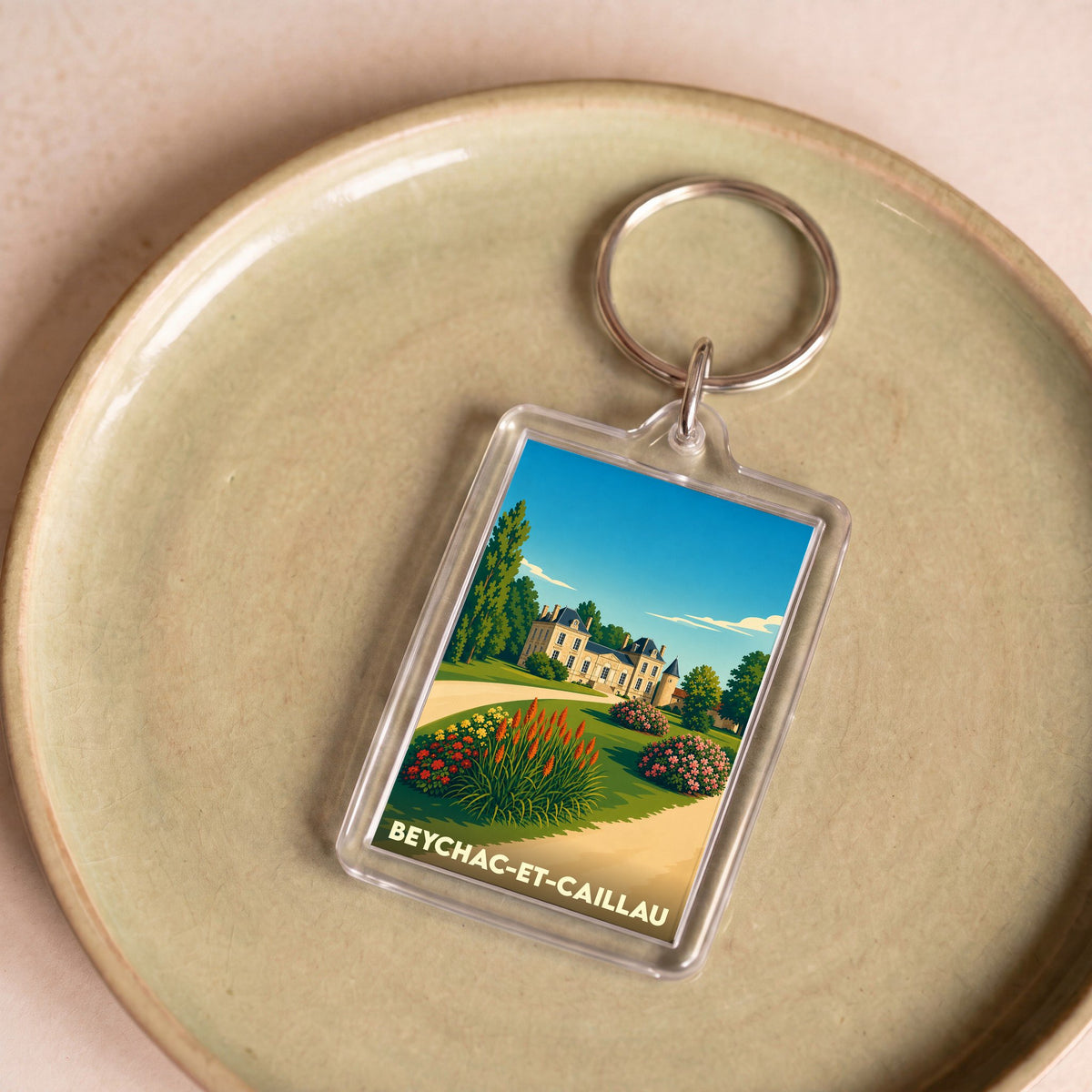 Porte-clés souvenir de la ville de Beychac-et-Caillau avec une illustration stylisée d'un château et de ses jardins.