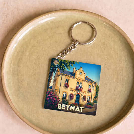 Porte-clés souvenir de la ville de Beynat avec une illustration stylisée de sa mairie fleurie.