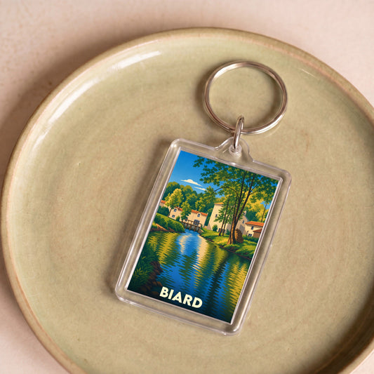 Porte-clés souvenir de la ville de Biard avec une illustration stylisée d'un paysage de rivière.