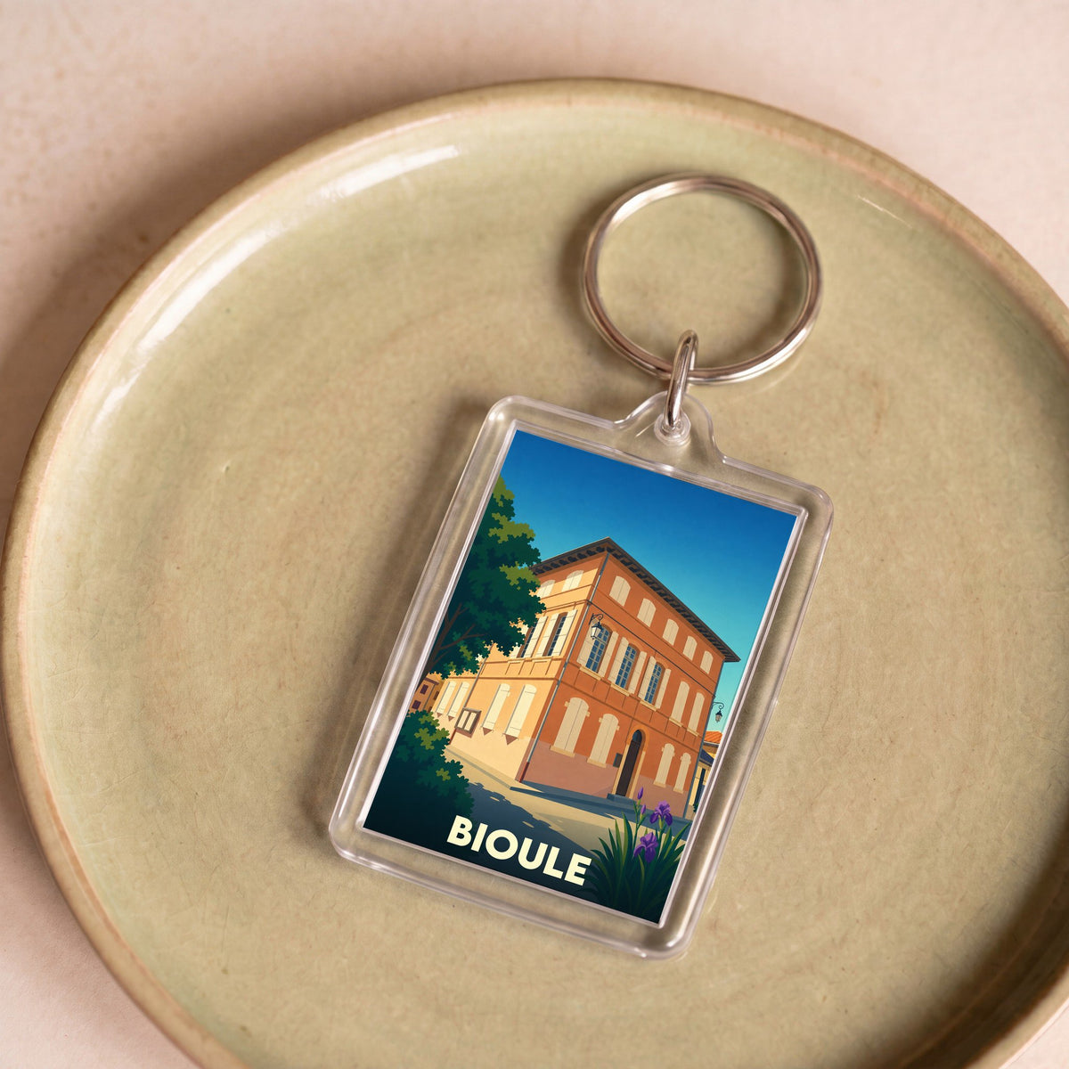 Porte-clés souvenir de la ville de Bioule avec une illustration stylisée d'un bâtiment historique.