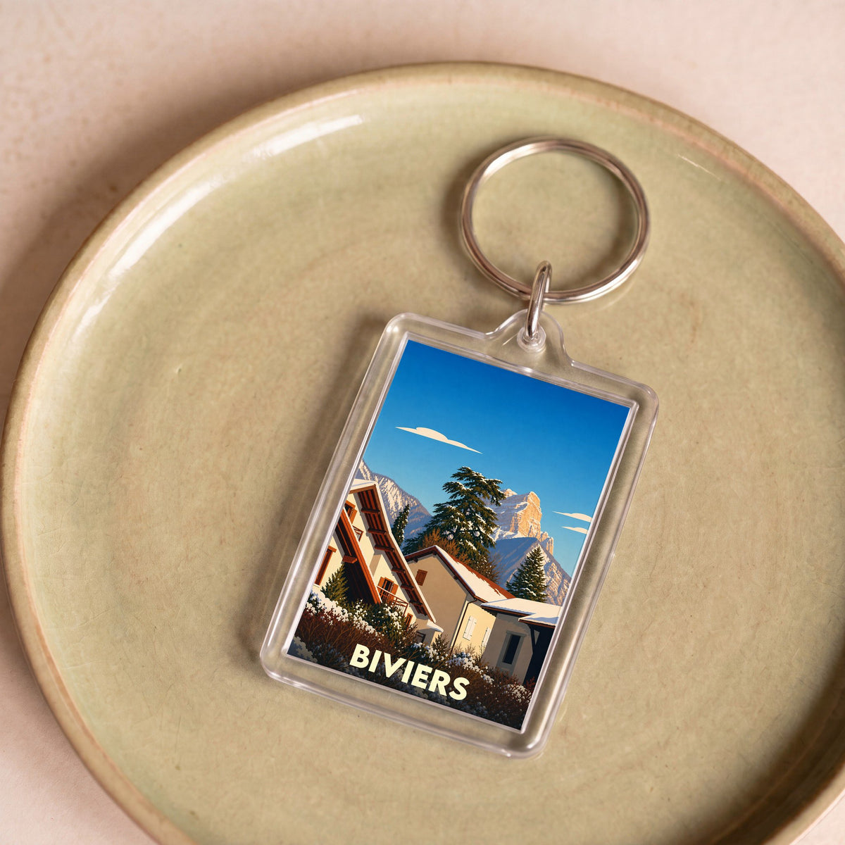 Porte-clés souvenir de la ville de Biviers avec une illustration stylisée de paysages enneigés.