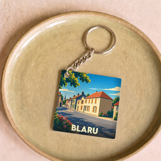 Porte-clés souvenir de la ville de Blaru avec une illustration stylisée d'une rue pittoresque.