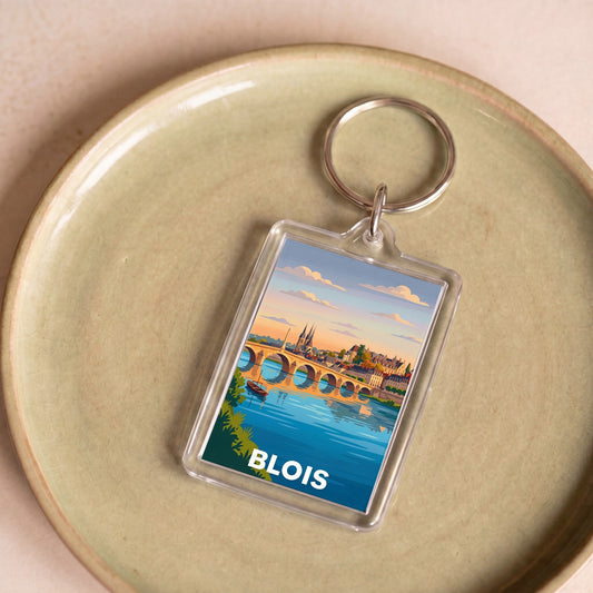 Porte-clés souvenir de la ville de Blois avec une illustration stylisée de son pont et de son château au coucher du soleil.