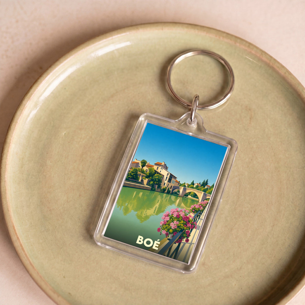 Porte-clés souvenir de la ville de Boé avec une illustration stylisée d'un paysage fluvial.