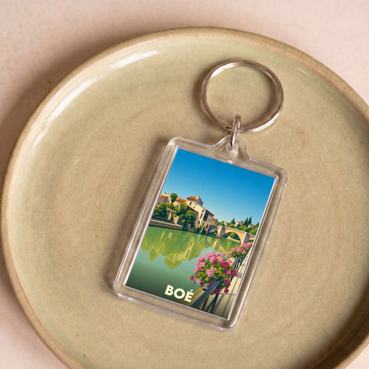 Porte-clés souvenir de la ville de Boé avec une illustration stylisée d'un paysage fluvial.