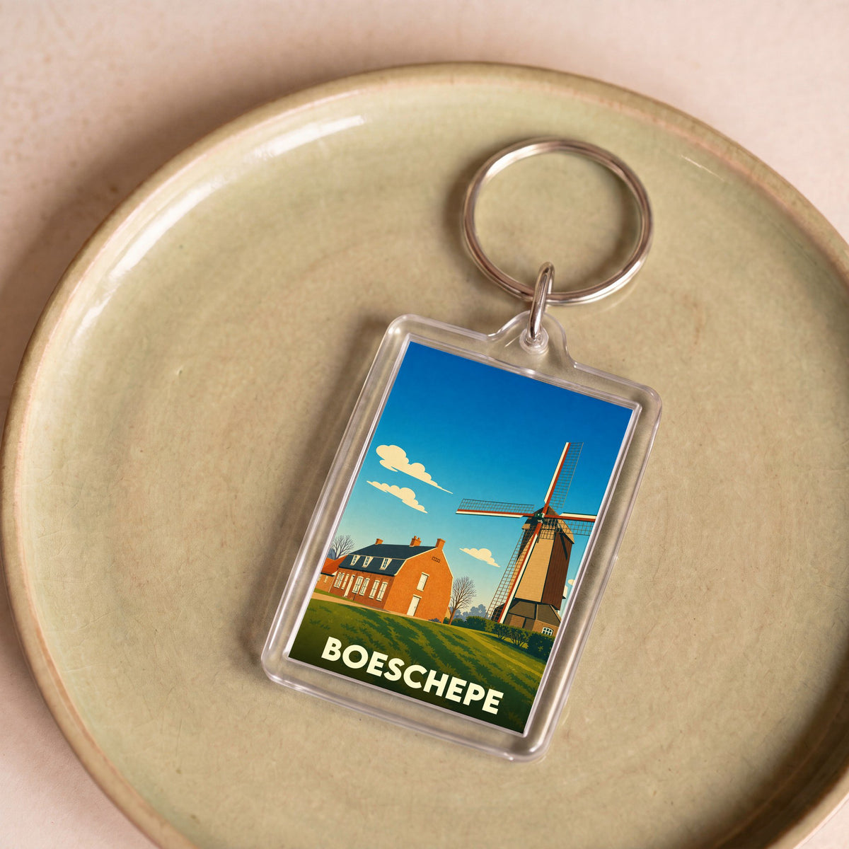 Porte-clés souvenir de la ville de Boeschepe avec une illustration stylisée d'un moulin et d'une maison flamande.