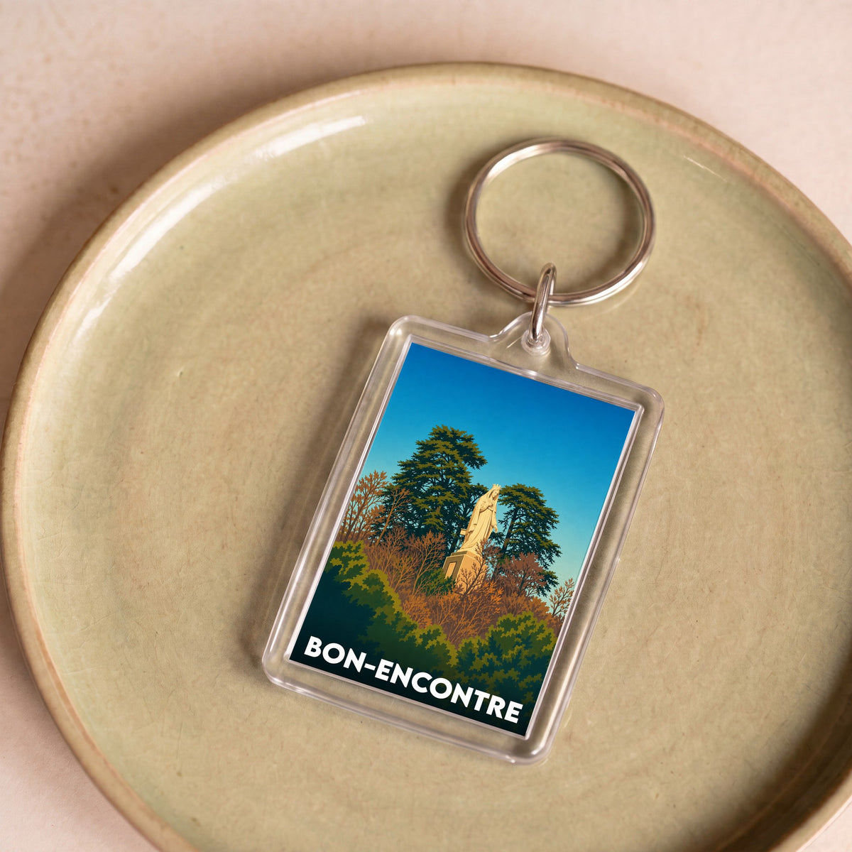 Porte-clés souvenir de la ville de Bon-Encontre avec une illustration stylisée d'une statue parmi les arbres.