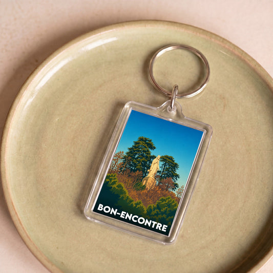 Porte-clés souvenir de la ville de Bon-Encontre avec une illustration stylisée d'une statue parmi les arbres.