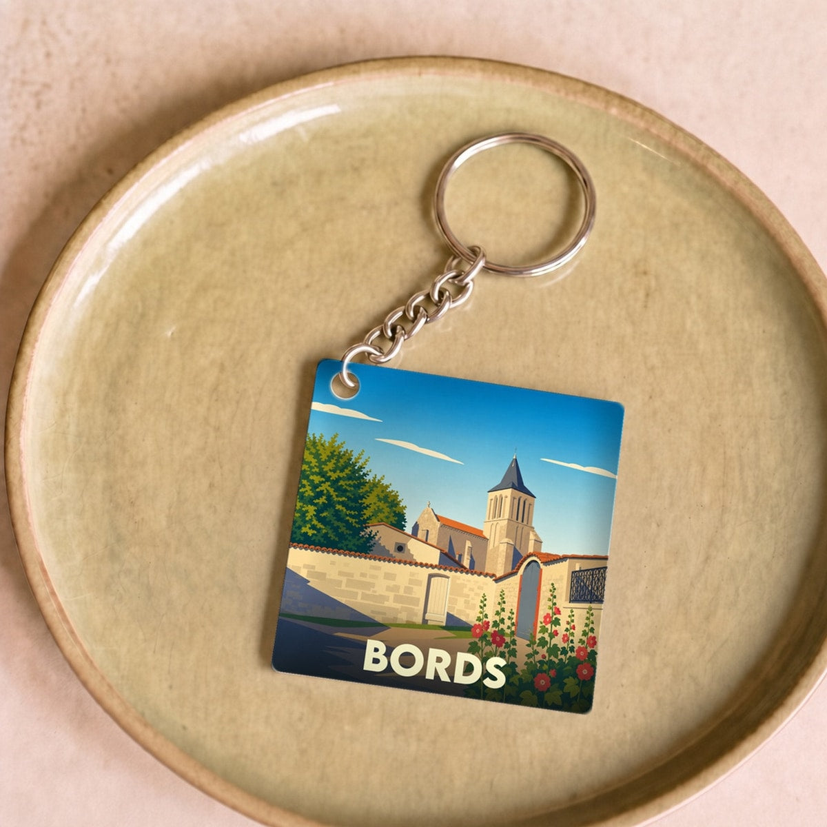 Porte-clés souvenir de la ville de Bords avec une illustration stylisée de son église et de ses remparts.