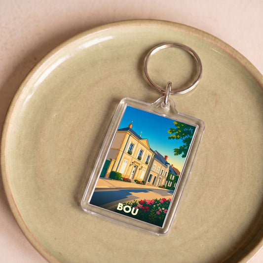 Porte-clés souvenir de la ville de Bou avec une illustration stylisée d'une rue ensoleillée.