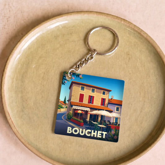 Porte-clés souvenir de la ville de Bouchet avec une illustration stylisée d'une terrasse de café.