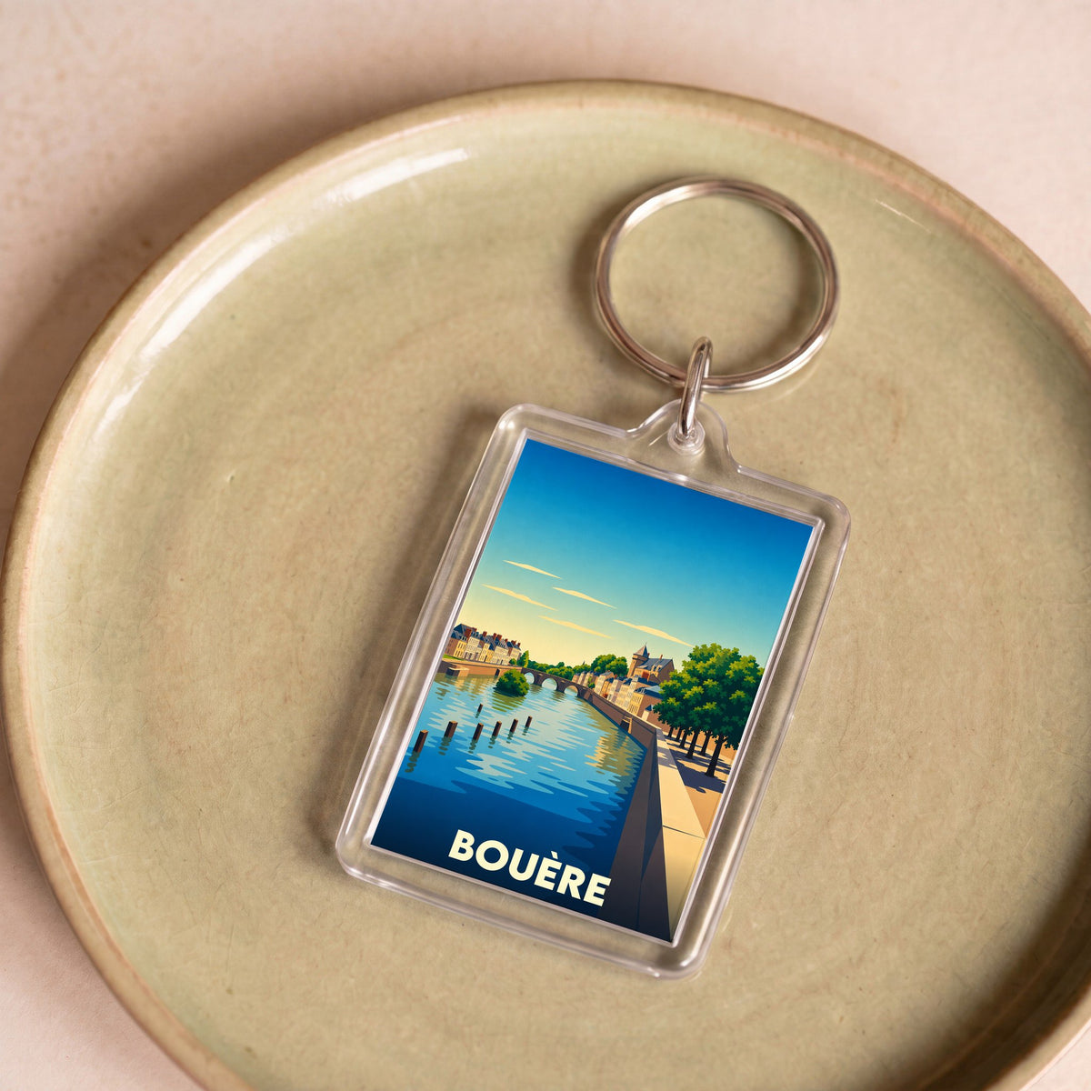 Porte-clés souvenir de la ville de Bouère avec une illustration stylisée d'un bord de rivière.