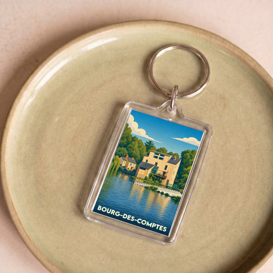 Porte-clés souvenir de la ville de Bourg-des-Comptes avec une illustration stylisée d'un moulin au bord de l'eau.