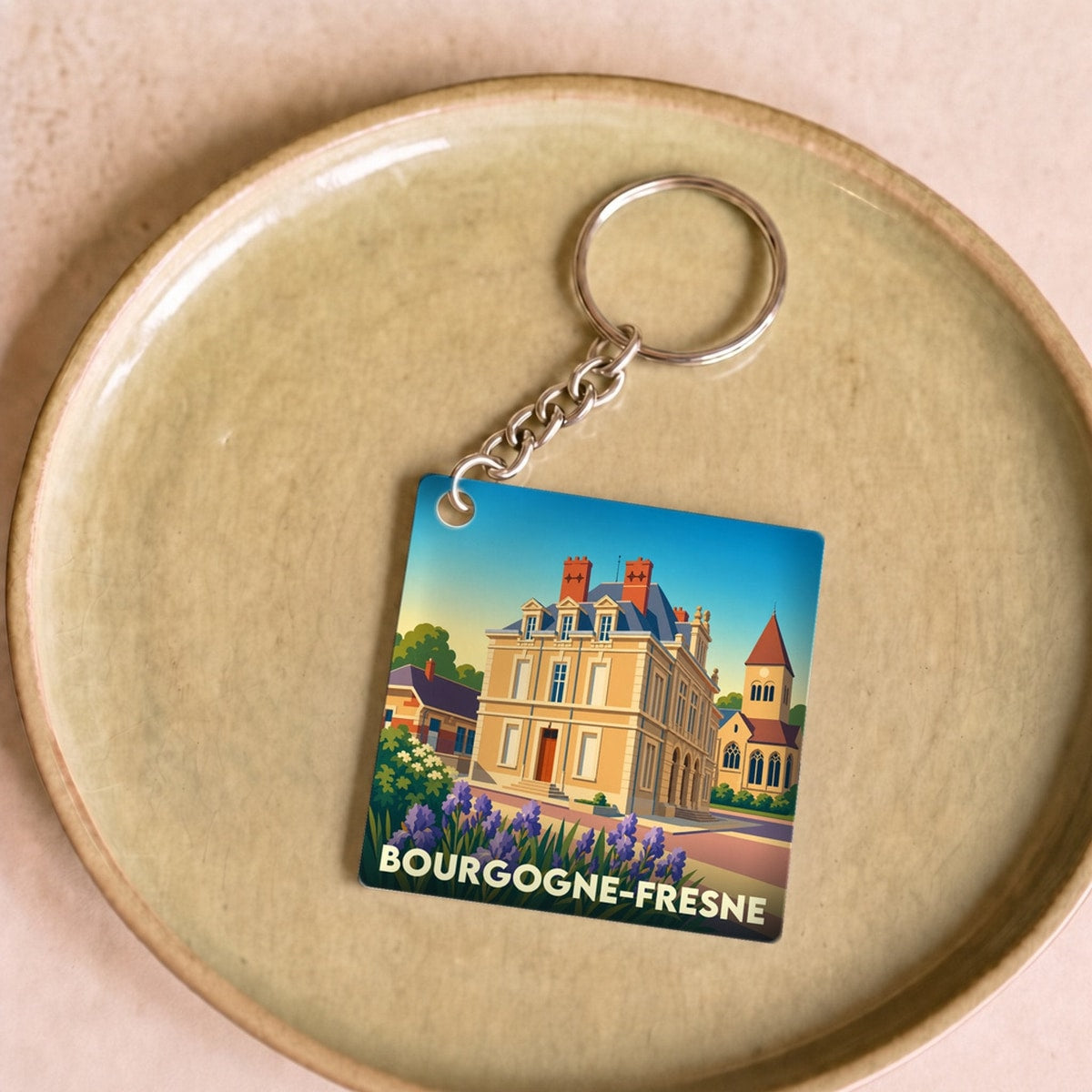 Porte-clés souvenir de la ville de Bourgogne-Fresne avec une illustration stylisée d'un bâtiment historique et de fleurs.